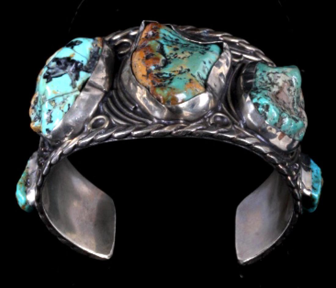Navajo Sterling Silver Turquoise Cuff: Featured in this lot we have a Navajo Native American sterling silver turquoise cuff. The cuff shows braided silver around the border, with small bands of silver ribs and small circles on the top. It 