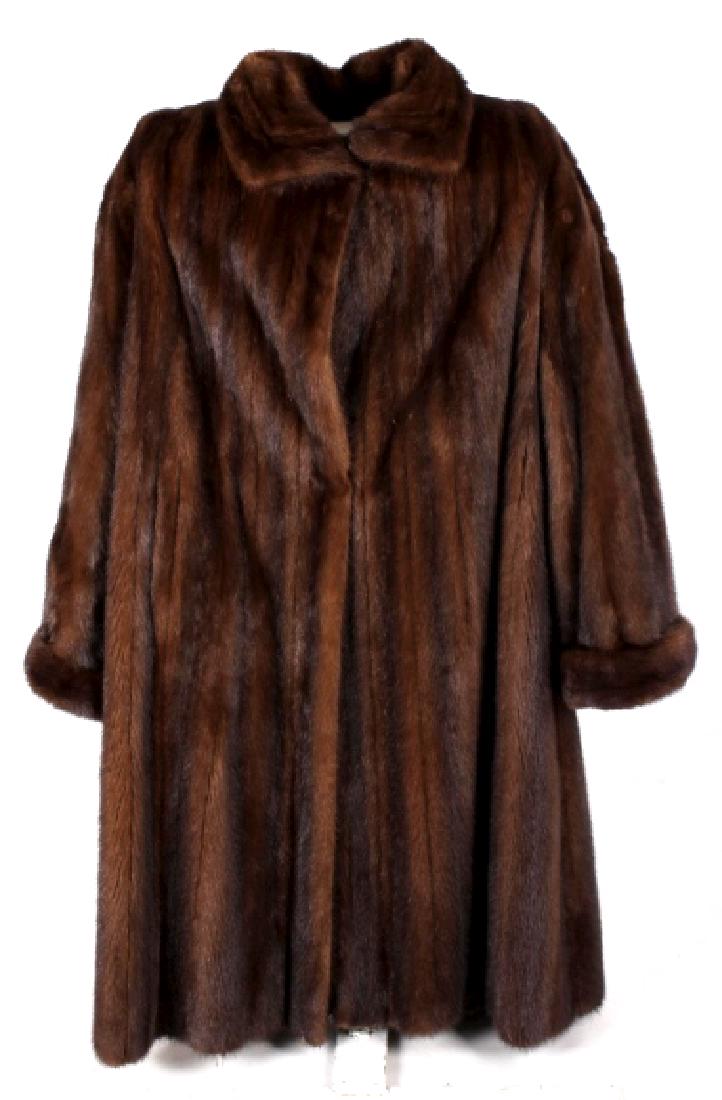 Ladies Full Length Mink Fur Coat: Featured in this lot we have a ladies full length mink fur coat. The coat features a mink fur exterior and a silk lined interior. The coat shows wonderful dark brown coloration and the silk is a choco