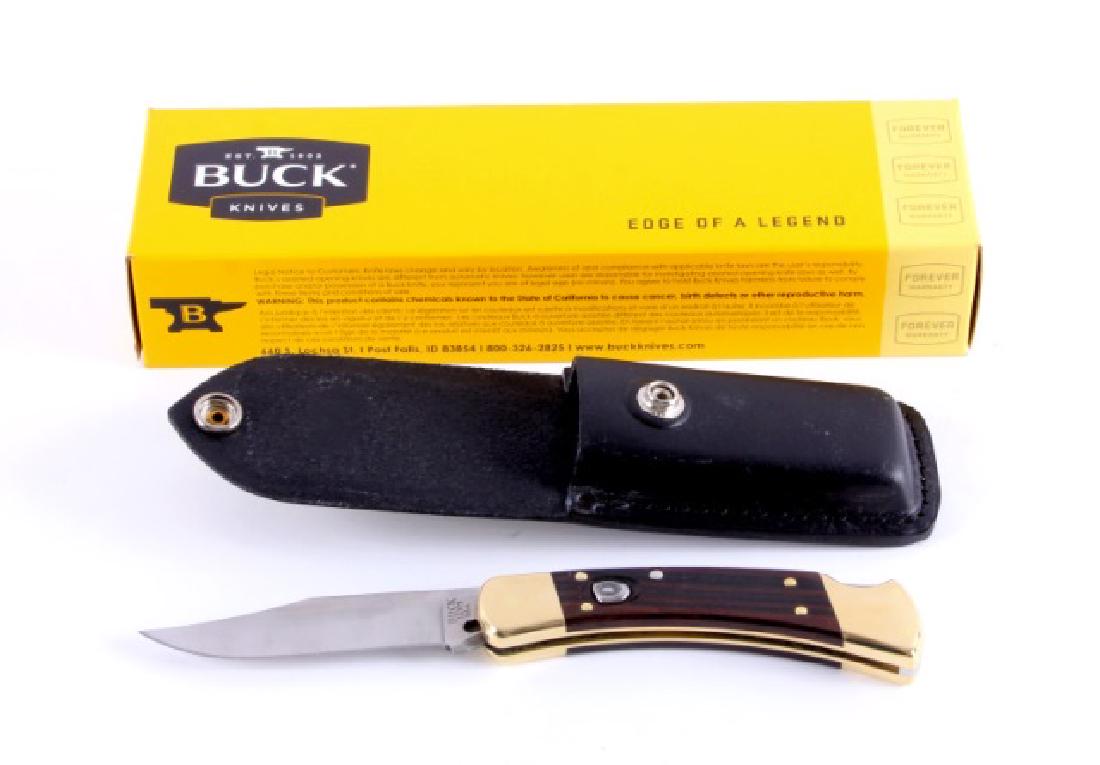 Buck 110 Automatic Push Button Knife New in Box: This is a new in box Buck 110 automatic push button knife with leather scabbard. The knife features a hardened steel clip point blade with brass bolsters and Ebony Dymondwood grips. The blade is marke