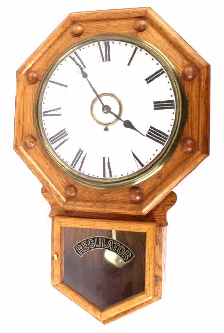 Antique Oak Regulator Wall Clock: This is an early antique regulator wall clock. The clock features a solid American oak case with a mechanical chiming movement. The piece shows a beautiful octagon top that holds the clock face. The g