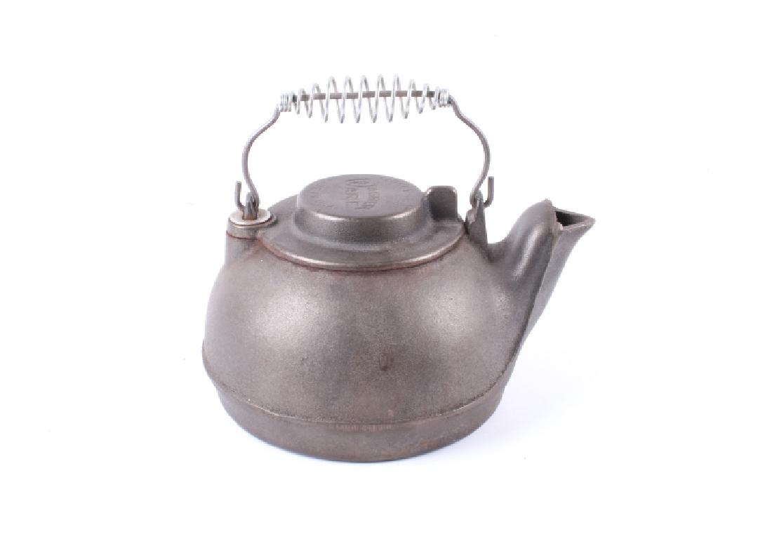 Antique Wagner Ware Cast Iron Tea Kettle: This lot features a beautiful antique Wagner Ware cast iron tea kettle. The top of the kettle is marked "SIDNEY OHIO WAGNER WARE MADE IN USA". The kettle measures 9.5" long, 7.5" wide, and 8" tall wit