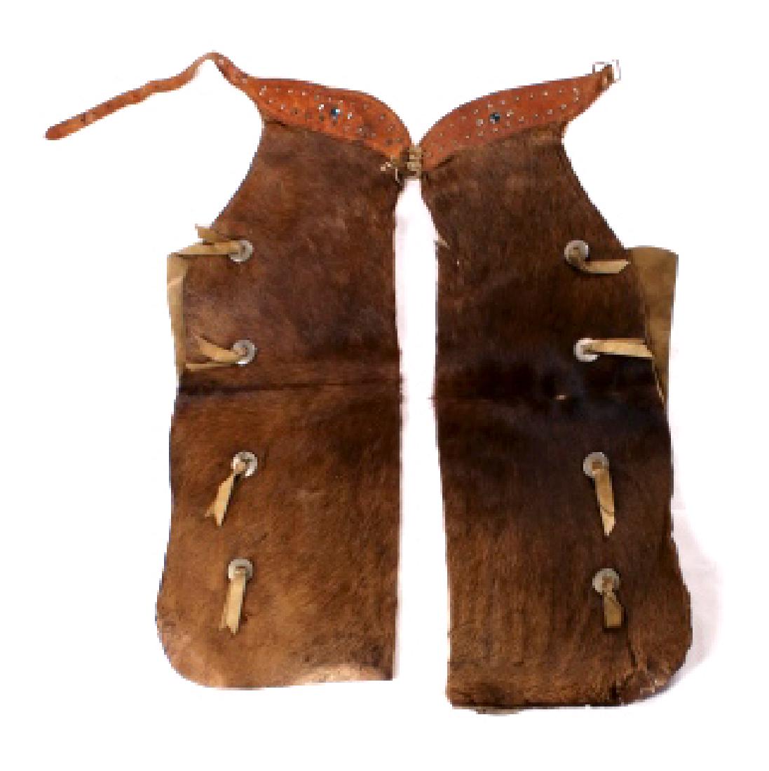 Montana Cowhide & Concho Cowboy Chaps 1900-1920: The lot features a wonderful set of light to dark brown colored Steer cowhide and leather studded chaps with conchos from a Montana Cowboy. The cowhide is a rich brown color and tan hide with four con