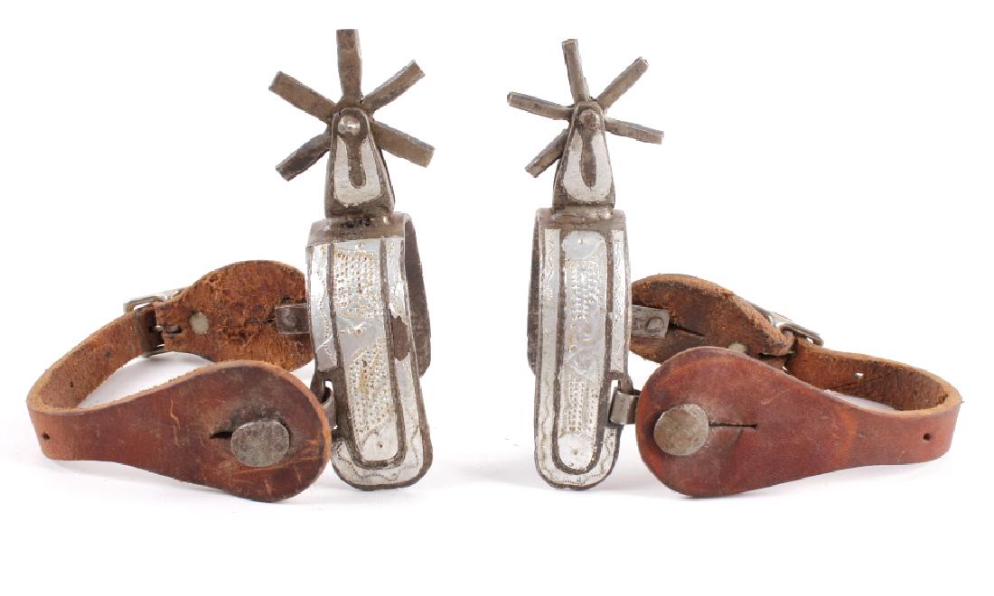 Silver Inlayed Chasing Spurs: Offered in this lot we have a pair of silver inlayed chasing spurs. The spurs are constructed out of iron with patterned silver inlays along the length of the spurs. The spurs are void of makers marks