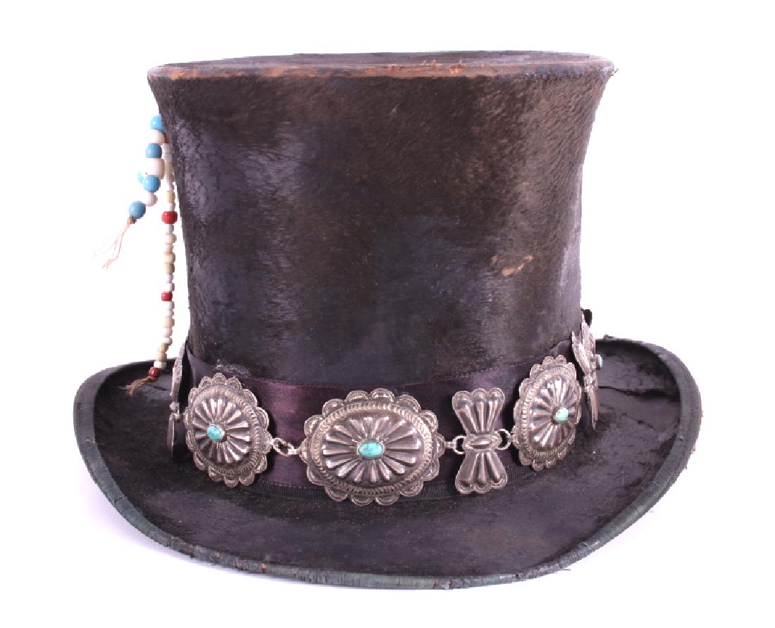 Navajo Native American Concho Top Hat: Included in this lot is a Sioux Native American concho top hat. The top hat is a John Sims manufactured in Chicago and constructed from Beaver pelt. The hat features a turquoise & silver concho belt. 