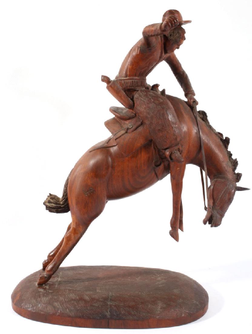 Black Americana Bucking Bronco Carving 19th C.: The lot features an original hand carved folk-art wood sculpture showing a Black Americana cowboy riding a bucking bronco and dating to the 19th Century. The piece shows a solid walnut construction an