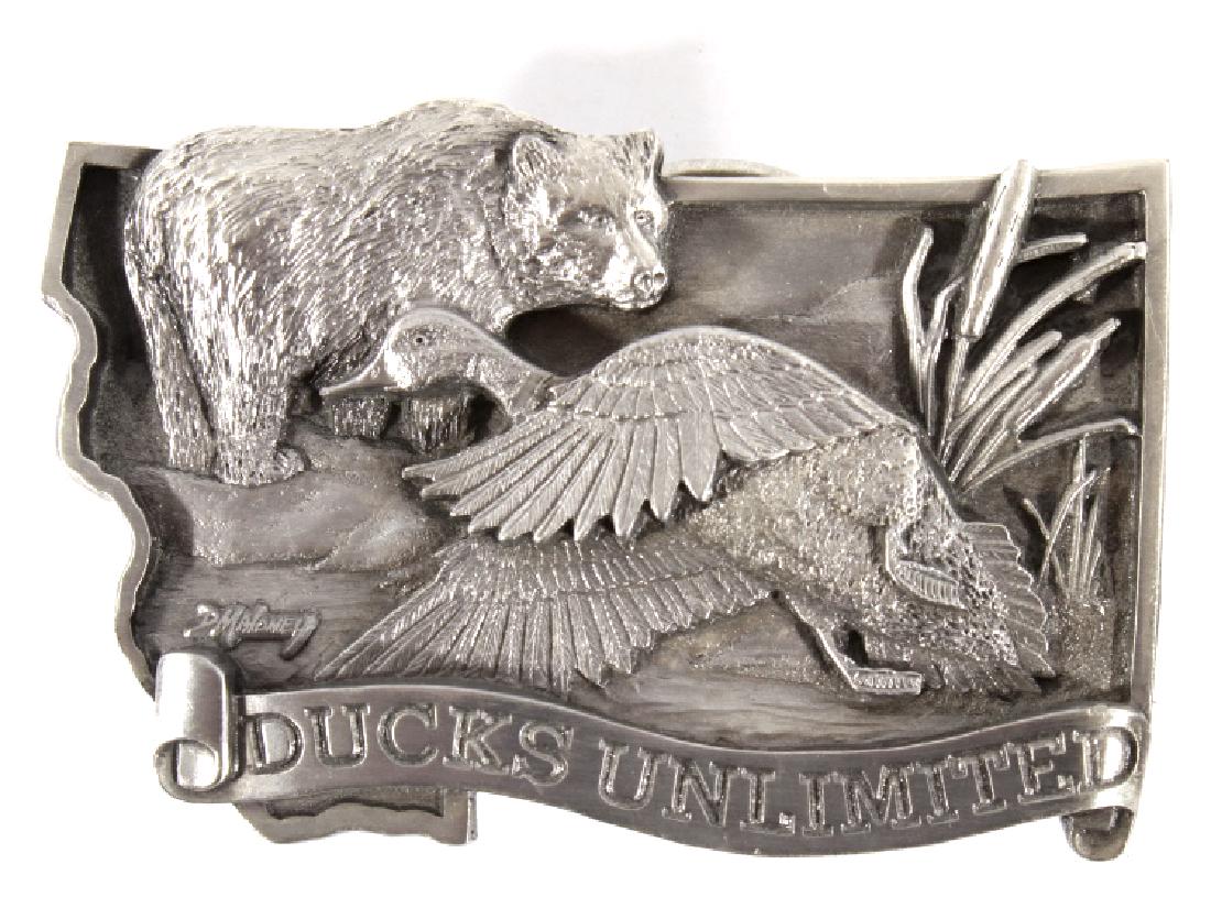 Ducks Unlimited Dave Maloney Belt Buckle 41/1500: Featured in this lot we have a Ducks Unlimited limited first edition belt buckle by Dave Maloney originating from circa 1984. Maloney is a professional Montana artist known for his landscapes and depi