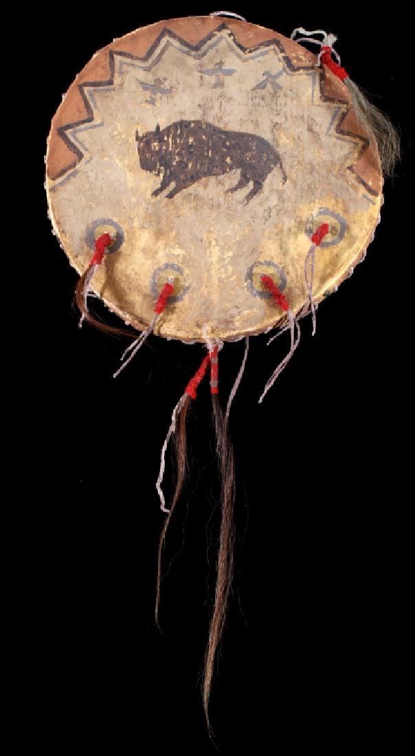 Sioux Polychrome Buffalo & Thunderbird War Shield: The lot features a stretched rawhide parfleche war shield with bent wood hoop from the Sioux Native American Indians. The piece shows a polychrome mineral painted surface with the large painting of a