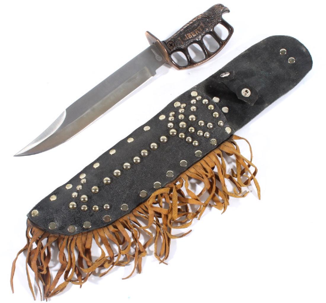 Liberty Knuckle Duster Knife with Leather Sheath: Featured in this lot we have a Liberty knuckle duster bowie knife with decorated leather sheath. The knife shows a stainless steel blade with a bronze grip. The grip is cast into the shape of a eagle 