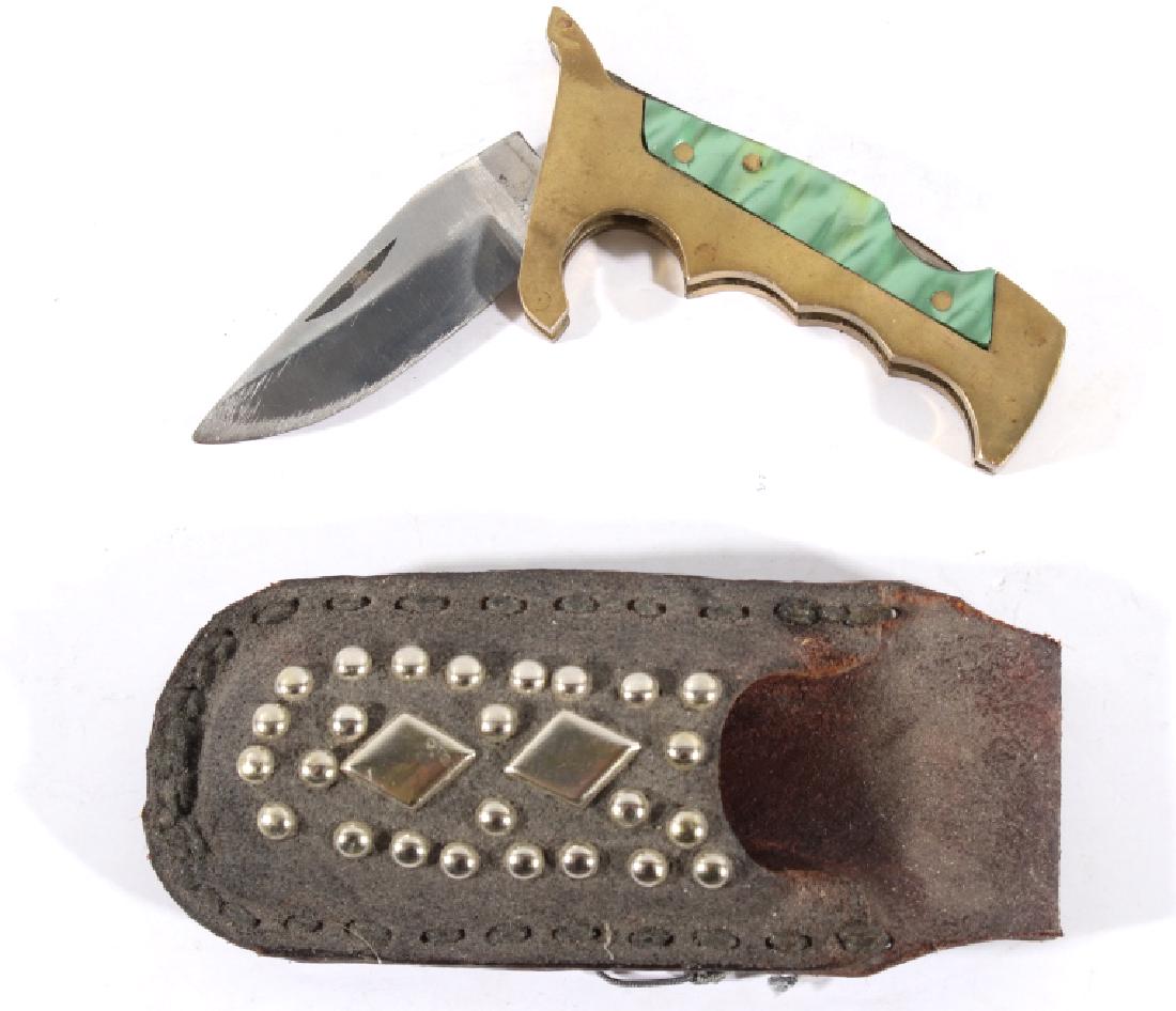 Brass Knuckles Folding Knife w/ Studded Case: Featured in this lot we have a steel and brass folding knife with decorated leather sheath. The knife showcases a stainless steel blade with a brass grip and built in guard. The handle shows brass con