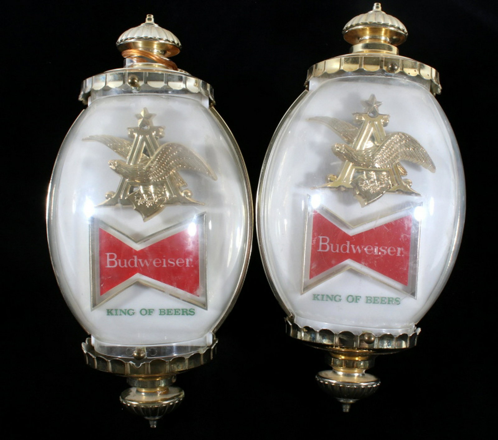 Budweiser King Of Beer Wall Lamps: Offered in this lot we have a pair of Budweiser King of Beer advertising wall lamps originating from the late 20th century. The sconce wall lamps show gold and white colored plastic construction with 