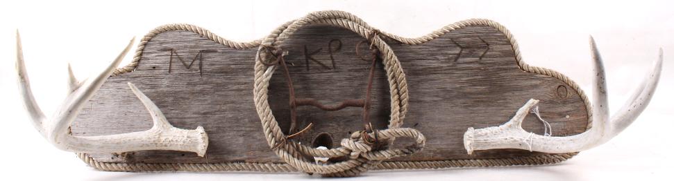 Branded Pine Wood Ranch Sign With Antlers: In this lot we have a branded sign that has rope wrapped around the sign. On the sign itself there is three different brands. "M", "KP" , and ">->". The middle of the sign has the coil of rope that is