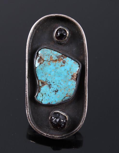 Signed Navajo Sterling Turquoise & Garnet Ring: Featured in this lot we have a signed Navajo Native American sterling silver turquoise and red garnet ring. The ring displays a sterling silver shadow box construction with a turquoise nugget set at t