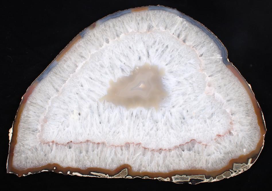 Large Cross Cut Quartz Crystal Geode: Available in this lot we have a large quartz crystal geode slice. The piece shows white, red, clear, and light brown crystal formations with a rocky shell. The geode is cut into a thin plate in the fu