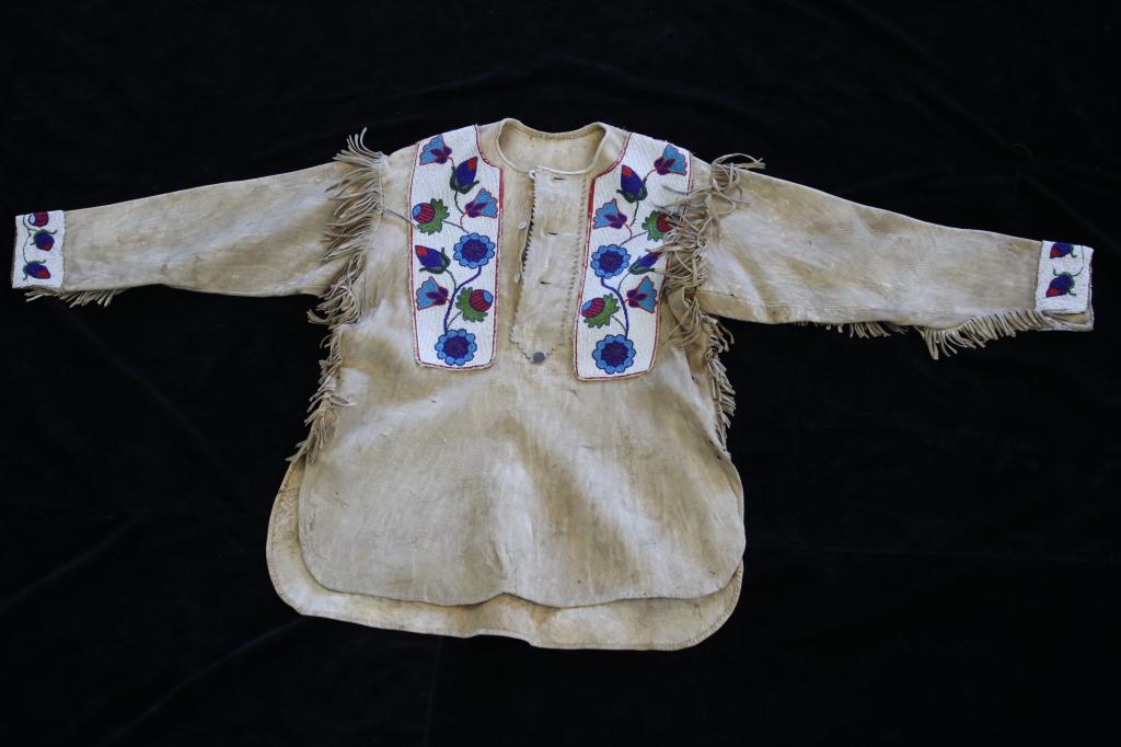Sioux Whimsical Beaded War Shirt Late19th Century: The lot features a fine whimsical floral beaded war shirt from the Sioux Native American Indians of the late-19th Century. The shirt shows a Buffalo Bison Indian tanned hide construction with heavy fu