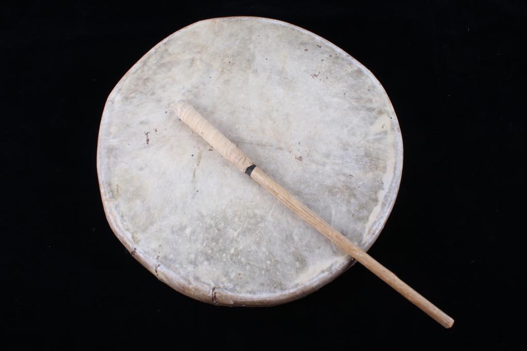 Blackfeet Indian Montana Rawhide Drum c. 1900's: Featured in this lot we have a Blackfeet Native American Indian Montana parfletche rawhide drum and beater stick originating from the 1900's. The piece shows a wetted and stretched parfleche rawhide f