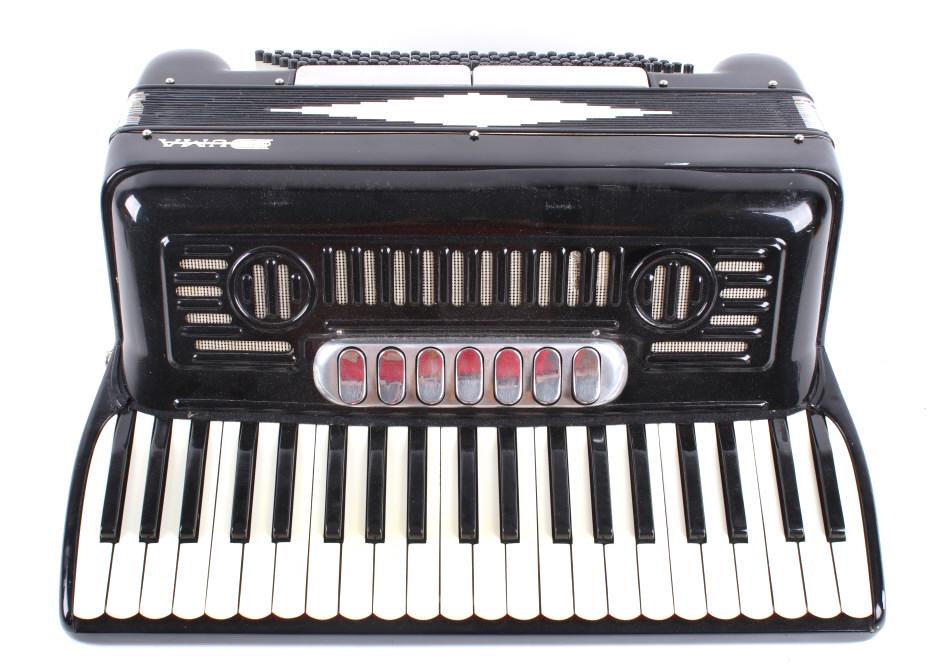 Duma Piano Accordion With Carry Case C. Late 1900s: Featured in this lot we have a Duma piano accordion with carry case originating from the late 1900's. The accordion displays 41 piano and 120 buttons on the side. The accordion shows a black and white