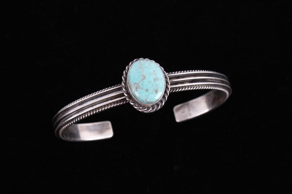 Navajo W Dawes Royston Turquoise Sterling Bracelet: Included in this lot is a Navajo Native American Wilson Dawes sterling silver and Royston turquoise bracelet. This beautiful thin band bracelet showcases a unique finned design and braided rope border