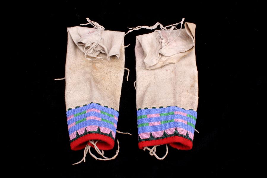 Sioux Beaded Hide Leggings c. 1890: The lot features a nice set of smaller beaded hide leggings from the Sioux Native American Indians from circa 1890-1900’s. The set shows an Indian tanned hide with a red stroud trade cloth edge and