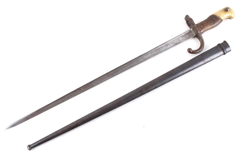 French M1874 WWI Sword Bayonet w/ Scabbard: Available in this lot is a French M1874 sword bayonet with metal scabbard originating from 1879. The piece shows a steel blade with a metal guard, wooden grip, and brass attachment point. The bayonet 
