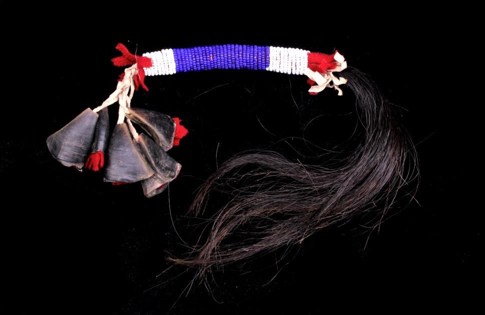 Northern Plains Beaded Dew Claw Quirt Dance Rattle: This is a unique, circa early to mid-1900’s quirt dance rattle from the Northern Plains Native American Indians. The piece shows Indian tanned hide and red trade cloth blanket with glass trade pony 
