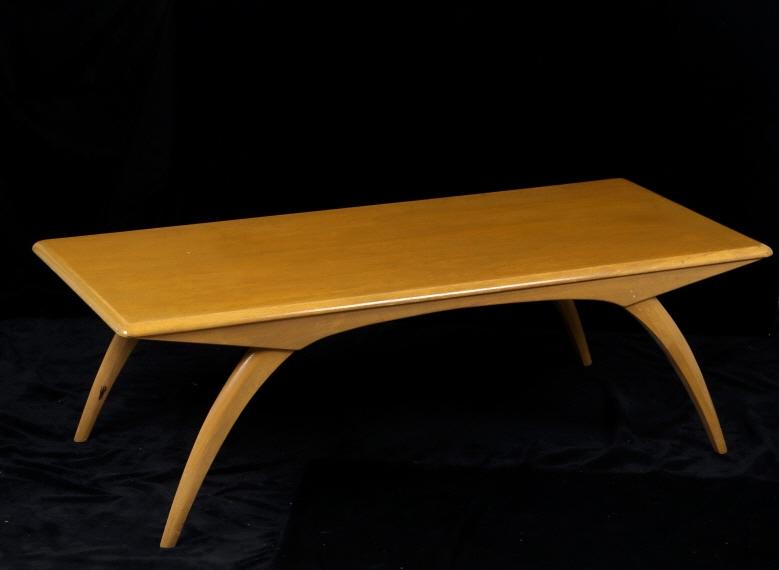 Mid 1900's Haywood Wakefield Coffee Table: Featured in this lot is a Haywood Wakefield coffee table originating from the mid 1900's. The table displays sturdy wooden construction with a gloss coating. The piece shows curved table legs with met