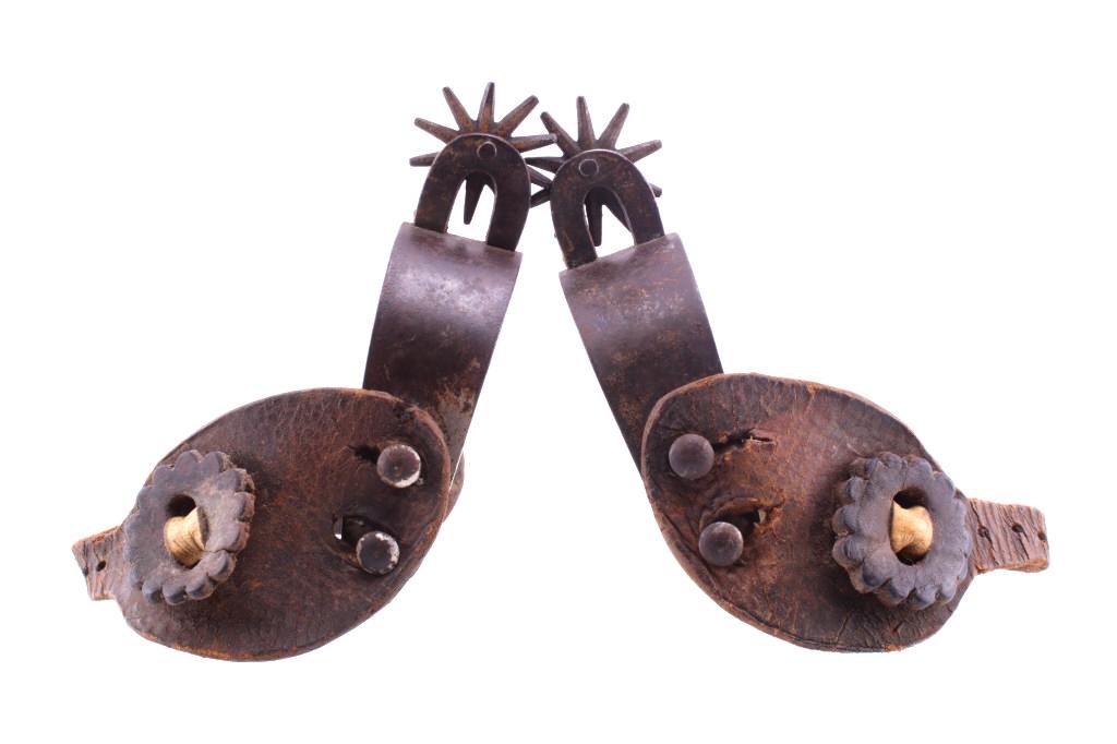 Vaquero Horseshoe Shank Spur Pair c. 1890-1910: Featured in this lot is this vaquero horseshoe shank spur pair, circa 1890-1910. The spurs show a flat snug design to the heel band, with heel band knobs and spur strap knobs shown on both sides of th