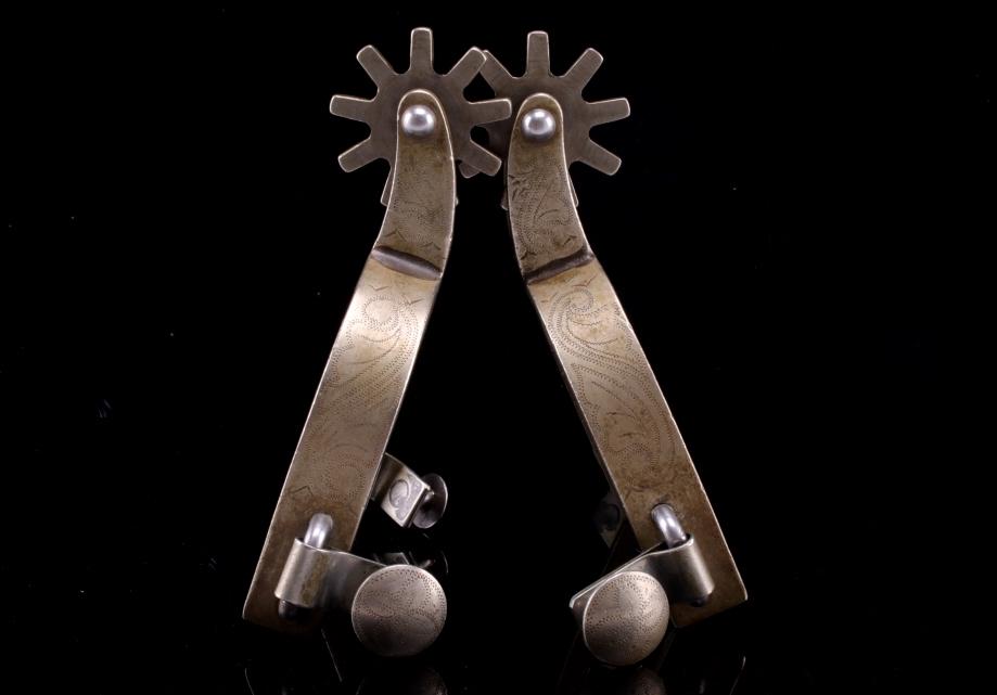 Ricardo Engraved Silver Spur Pair c. 1940s: Featured in this lot is this Ricardo engraved Alpaca silver spur pair, c. 1940's.The spurs show wonderful engraved silver construction with nine star rowels and swivel strap lugs. The artist’s hallm