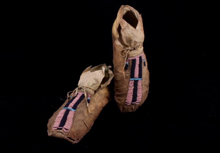 Crow Apsaalooke Beaded Moccasins c. 1890: The lot features a set of beaded, hard soled hide moccasins from the Crow Apsaalooke Native American Indians of Montana, dating to circa Pre-1890. The set features hard soled, parfleche rawhide bases 