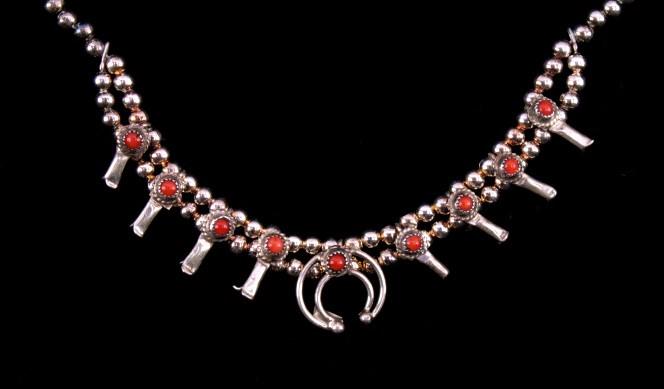 Navajo Sterling & Coral Squash Blossom Necklace: Included in this lot is a small Navajo Native American sterling silver and coral squash blossom necklace. This fine piece shows a small central Naja pendant with four squash blossoms on each side. Eac