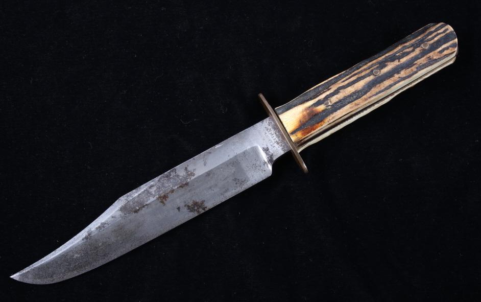 Sheffield Antler Handle Hunting Knife & Sheath: Included in this lot we have a Sheffield antler handle bowie hunting knife and leather sheath. The knife displays steel bowie style clip point blade, brass guard, and antler scale grips. The blade dis