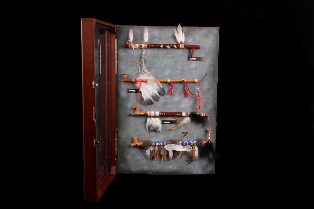 Shadow Box Collection of Calumet Pipes: This lot features four Calumet pipes in a shadow box case. The first pipe (circa 1880) is from modern day Oklahoma and is brown with silver bird pieces attached. The pipe also features a nice variatio