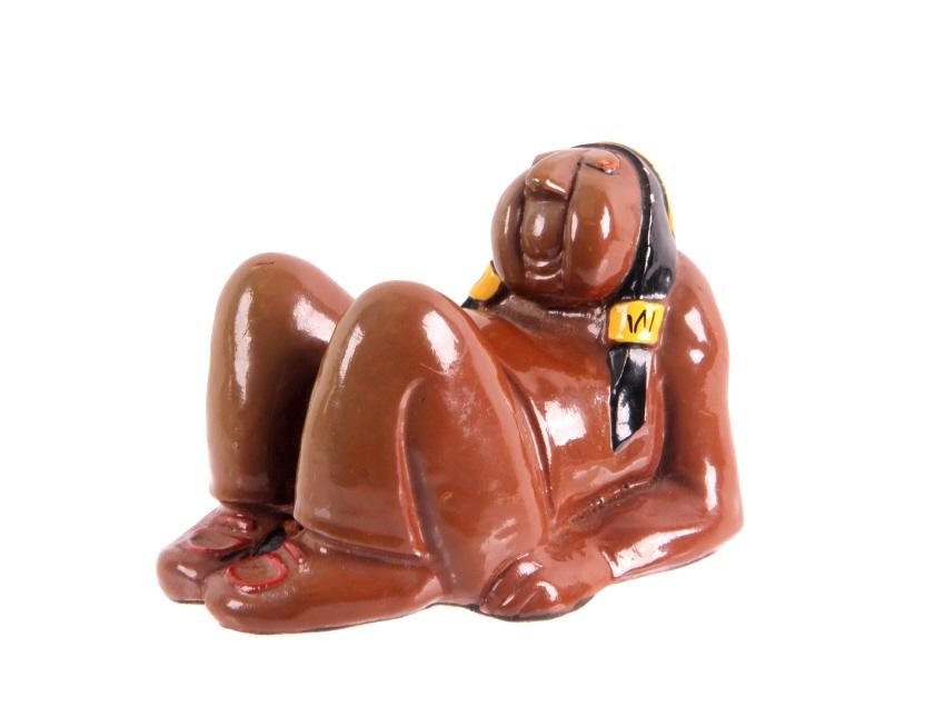 Lounging Native American Glazed Figurine c. 1947: This lot features a Lounging Native American Women Statue signed 'RA' 1947 and shown marked on the back. The statue features a brown body with black hair and yellow adornments. Connected to the back o