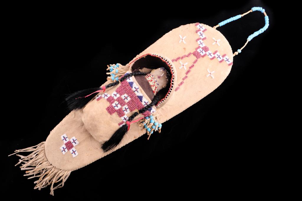 Rare Crow Beaded Cradle Board Papoose c. 1890: This is an exceptionally rare Montana Crow Late-19th Century Indian tanned hide and beaded cradle board papoose. The piece shows a wood backing frame that is completely covered in parfleche rawhide an