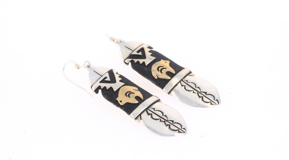 Navajo T&R Singer Sterling & 14K Gold Earrings: Featured in this lot is this sterling silver and 14k gold overlay earring pair from Navajo artist Tommy & Rose Singer. This pair of earrings show wonderfully and professionally crafted sterling silver