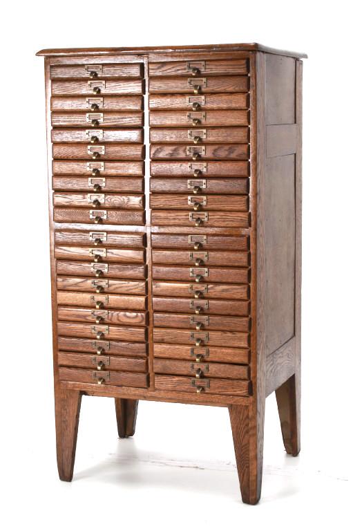 Hamilton MFG Type Set Oak File Cabinet c. 1900-: Featured in this lot is this type set file cabinet attributed to an early Hamilton style and circa 1900's. There are 40 drawers on this cabinet. The handles are modern additions but the rest of the ca