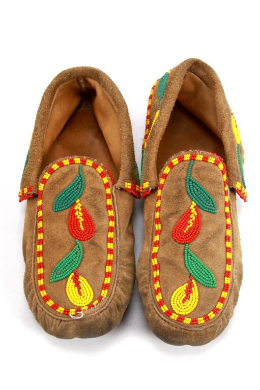 Montana Blackfoot Beaded Moccasins: The lot features a set of tanned hide leather and beaded moccasins from the Montana Blackfoot Native American Indians. The set shows a tanned leather hide construction with folded over ankle and whims
