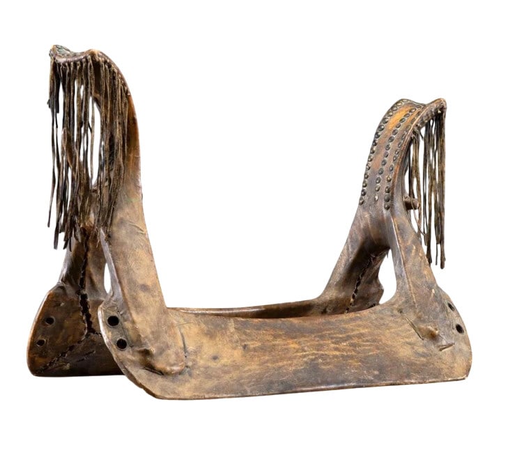 19th C. Southern Plains Tacked Rawhide Saddle: The lot features a 19th-century Southern Plains woman?s saddle from an-ex Sinking Springs, Ohio collection, a former March in Montana sale and Cowan's sale. The saddle exhibits a carved wooden tree fr
