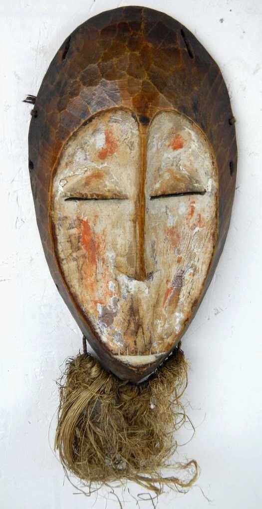 Gabon African Ghost Spirit Mask: This is a hand carved mask from the ancient people of Gabon Africa. This has beautiful patina with a painted face and a grass beard. This mask is early 1900-late 1800's. Measures 5.5"x10" with a 6" be