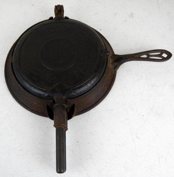 "The American" Waffle Iron by Griswold: This is an older cast iron waffle iron and stand by the most collectible maker Griswold. This piece is unique in that having the name "The American" on the front dates this piece to be 1800's.