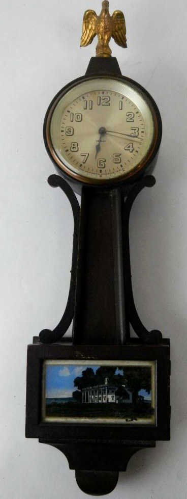 Antique New Haven Wall Clock: This is a wind up 12 day clock with beveled glass face, bald eagle metal statue, and glass door with art. In good condition. Measures 18" long