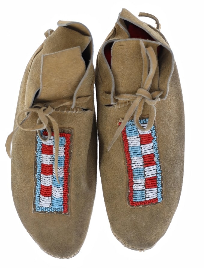 Northern Cheyenne Men's Beaded Hide Moccasins: The lot features a large set of men's beaded hide moccasins from the Northern Cheyenne possibly from Spotted Horse, Wyoming. The set is from the mid-1900's showing a tanned thick hide top with parflec