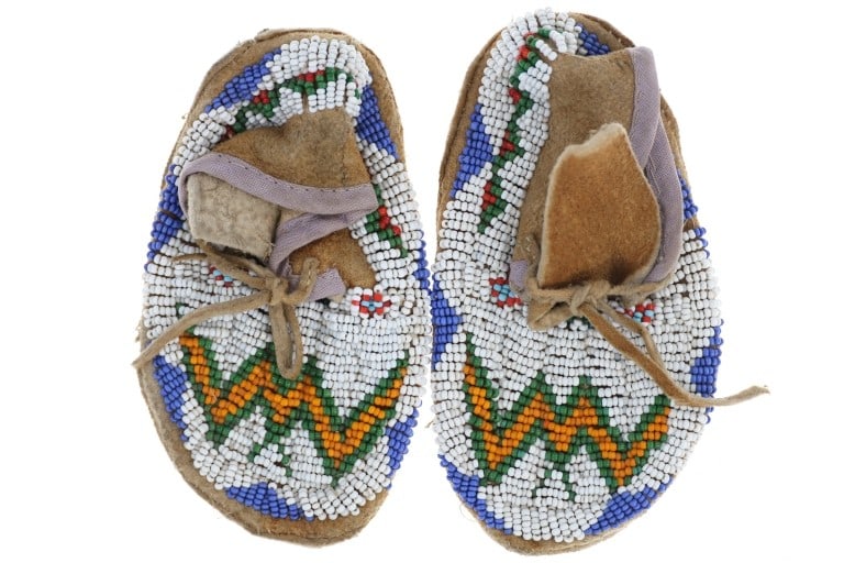 Ca. 1940- Blackfeet Beaded Child's Moccasins: The lot features a set of child's beaded moccasins from the Blackfeet / Blackfoot of Northern Montana from circa 1940-1950's. The set shows a nice thick Indian tanned hide with trade with thick sole b