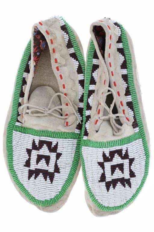 Montana Blackfoot Men's Beaded Moccasins ca. 1950-: The lot features a set of Montana Blackfoot / Blackfeet beaded Indian hide men's moccasins from circa 1950-1970's. The set shows Indian hide construction with foot worn soles showing glass trade beadw