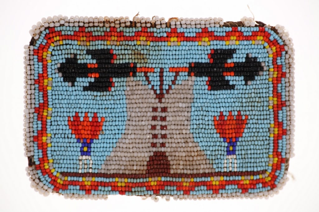C.a. 1950's Flathead Beaded Belt Buckle from Mont.: The lot features a circa 1950's beaded belt buckle from the Flathead Native American Indians from Montana. The buckle shows hide wrapping covered in glass trade seed beads with a tipi, peyote bird or