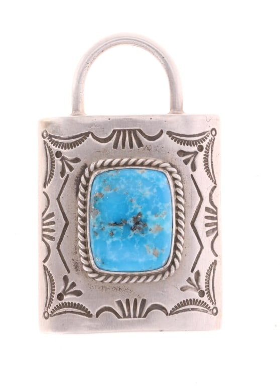 Navajo C. Johnson Sterling Silver Lock Pendant: Featured in this lot is this sterling silver and turquoise lock pendant from Navajo artist Charles Johnson. The pendant features a wonderfully and professionally crafted sterling silver and turquoise 