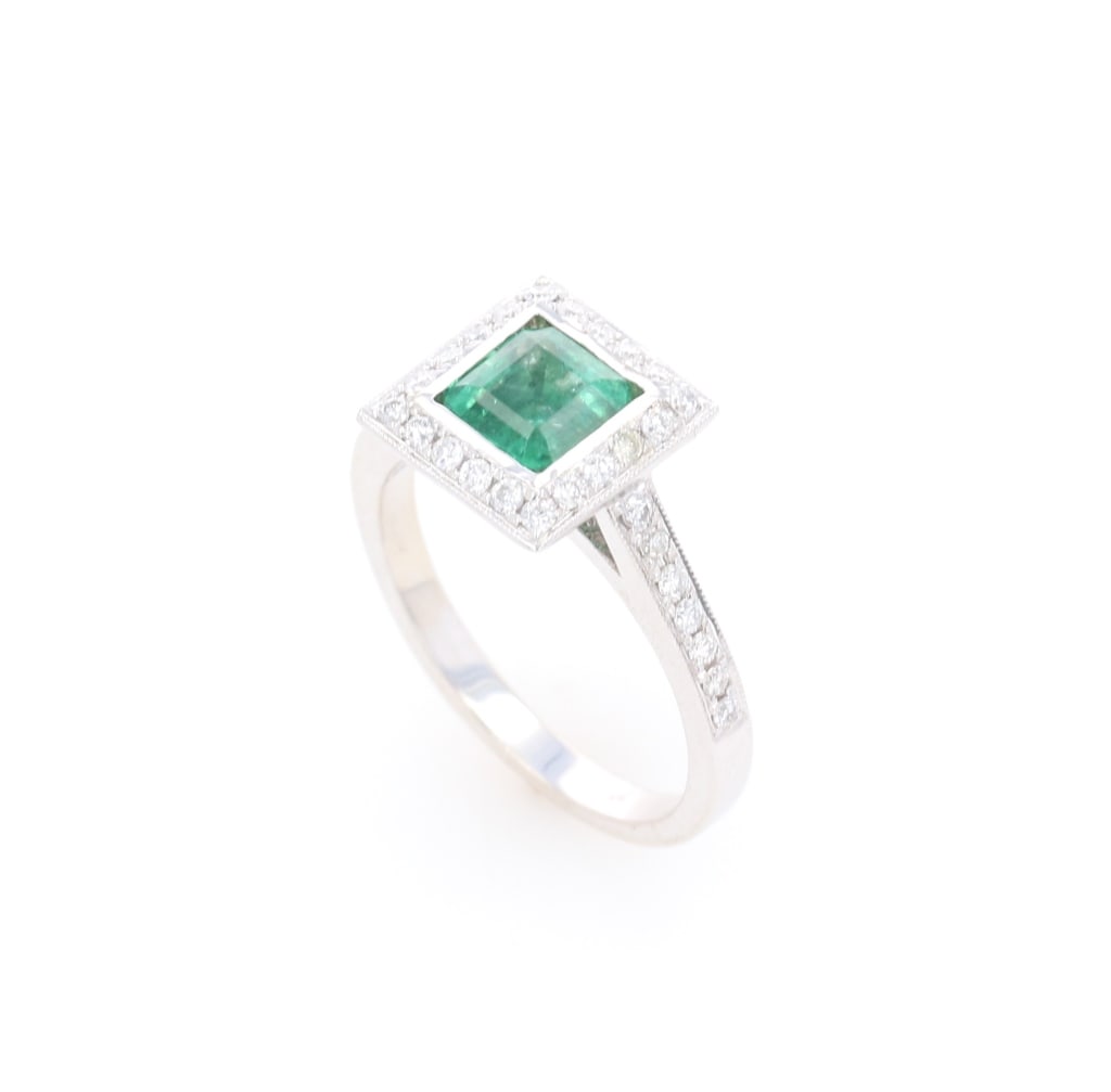 18k White Gold Emerald and Diamond Ring: Featured in this lot is this 18k White Gold Emerald and Diamond Ring with a bright finish. The ring features a wonderfully and professionally crafted 18K white gold construction with a centre mounted 