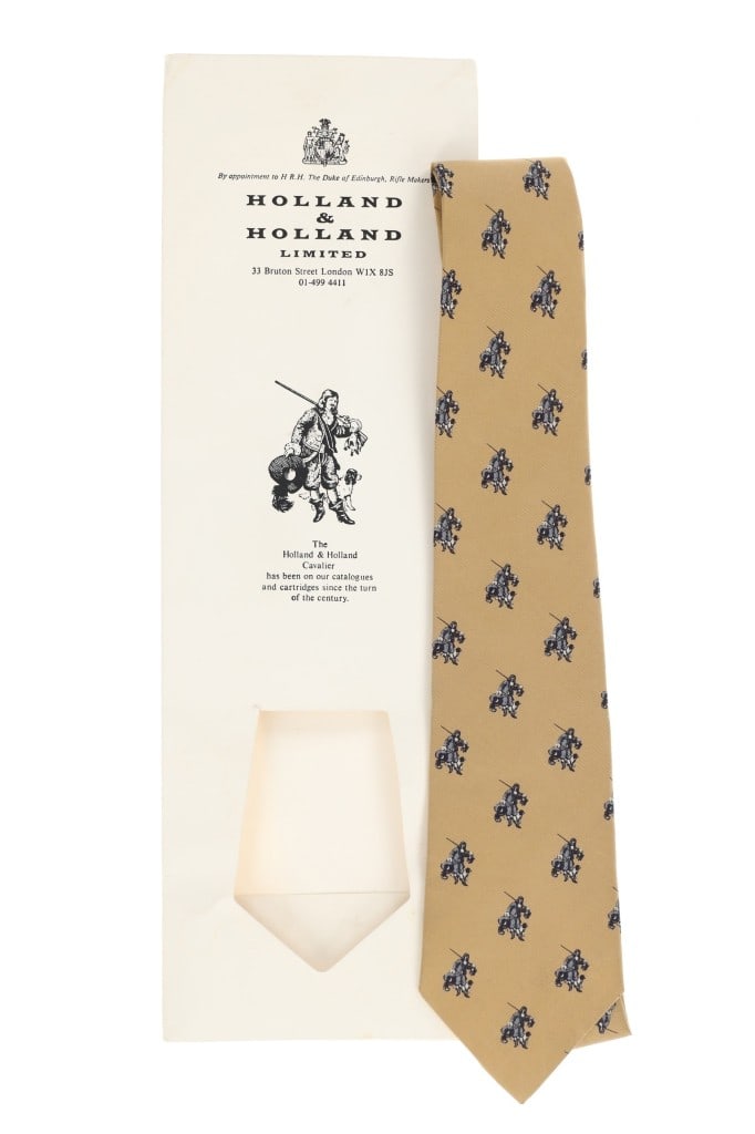 Vintage Holland & Holland Ltd. Silk Neck Tie: Offered in this lot is a Vintage Holland & Holland Limited Cavalier Logo Silk Neck Tie, New Old Stock, hand made in England. This gold coloured tie features the Holland & Holland "Cavalier" logo desig
