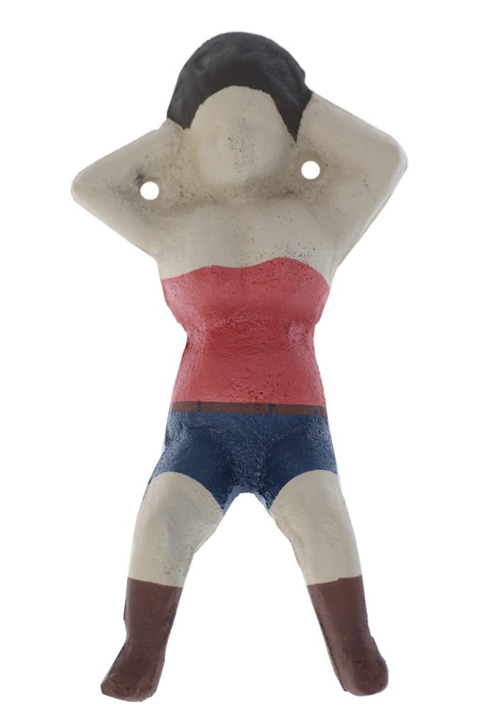 Rare Naughty Nellie Bootjack Cast Iron: The lot features a cast iron and hand painted Naughty Nellie bootjack with paper. The bootjack is from the 20th-century and was used to take cowboy boots off. It depicts a woman laying on her back wit