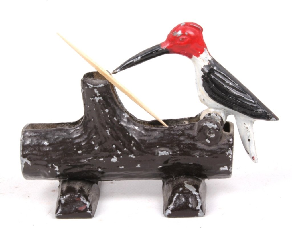 Antique Cast Iron Toothpick Woodpecker: This is a cast iron tooth pick holder which features a painted woodpecker siting on a log. The woodpecker is spring loaded and grabs a tooth pick when pushed down. This measures 4.75" long, 3.25" tall