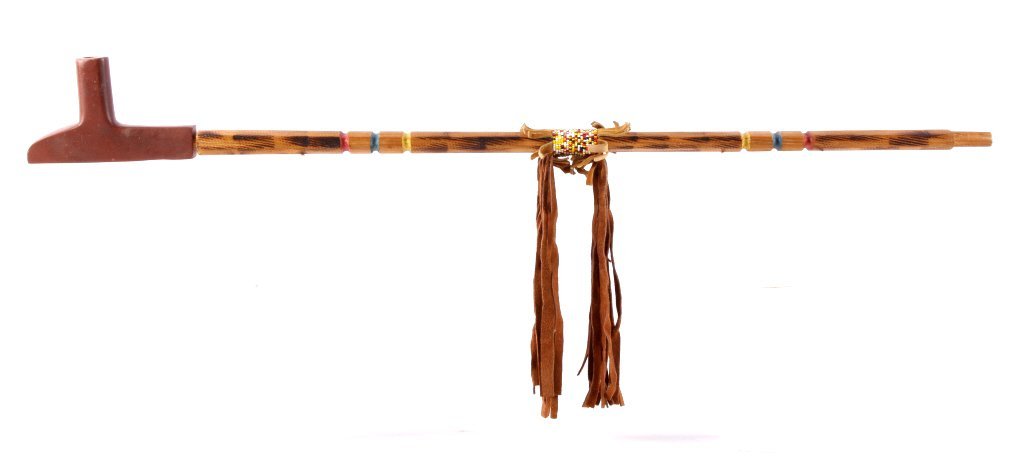Lakota Sioux Wood & Stone Pipe circa 1960's The lo: The lot features a Lakota Sioux Native American Indian pipe stem and bowl. The bowl shows a carved Pipestone or Catlinite T shape. The stem is carved wood showing file burns, yellow blue and red paint